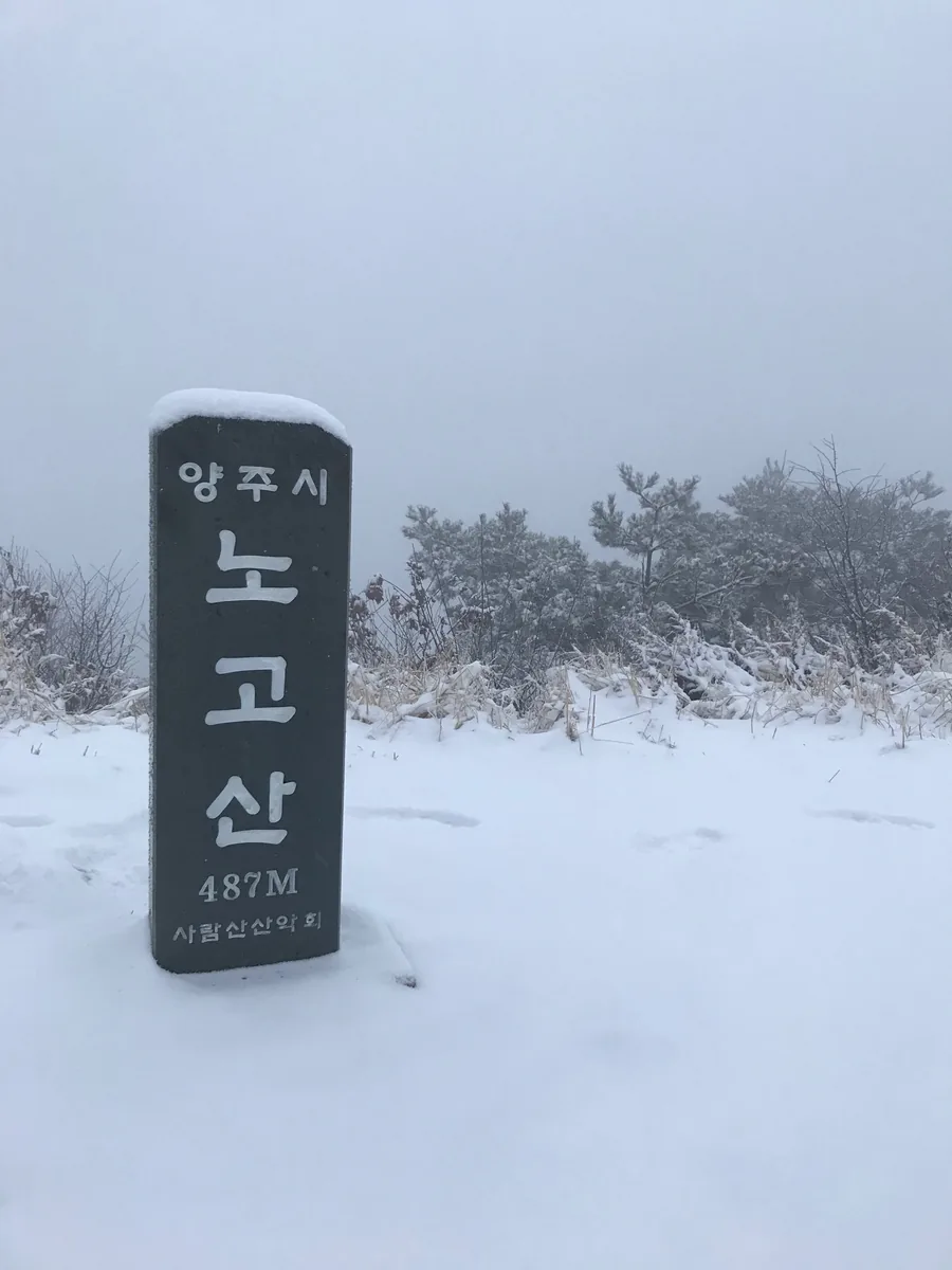 눈 속에 서 있는 노고산 정상석
